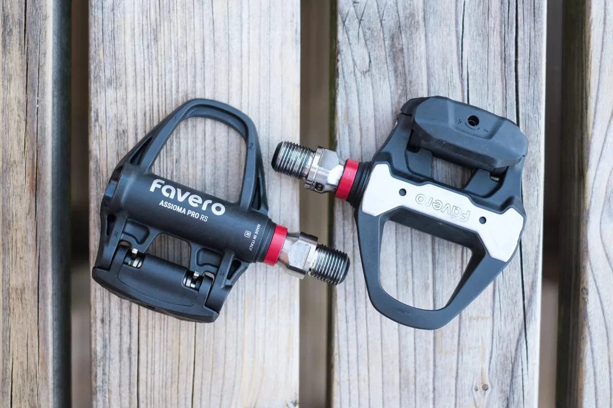 Favero Assioma PRO RS power meter pedals on wood surface, showing dual-sided design and lightweight construction.