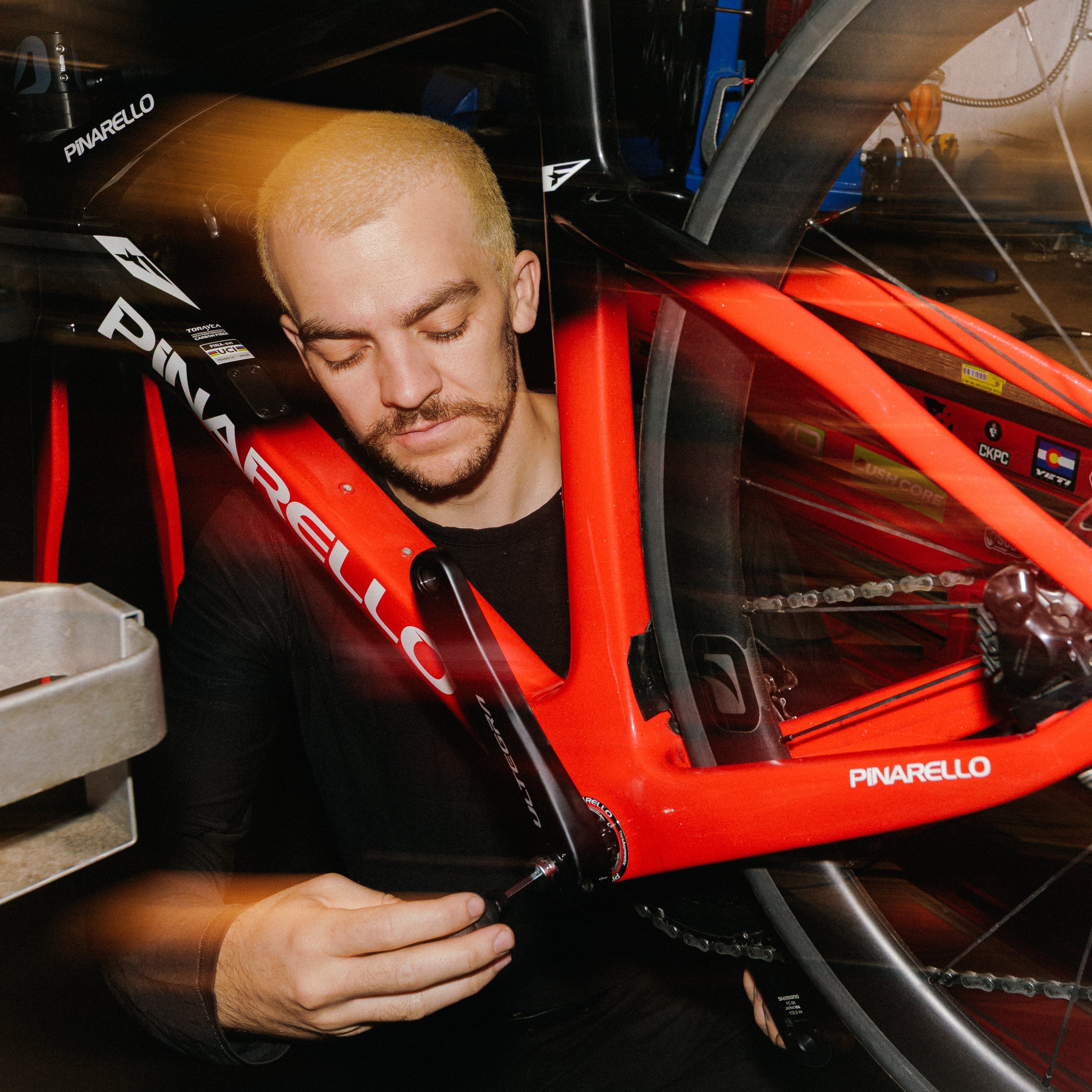 Person working on a Pinarello bicycle frame in a workshop.