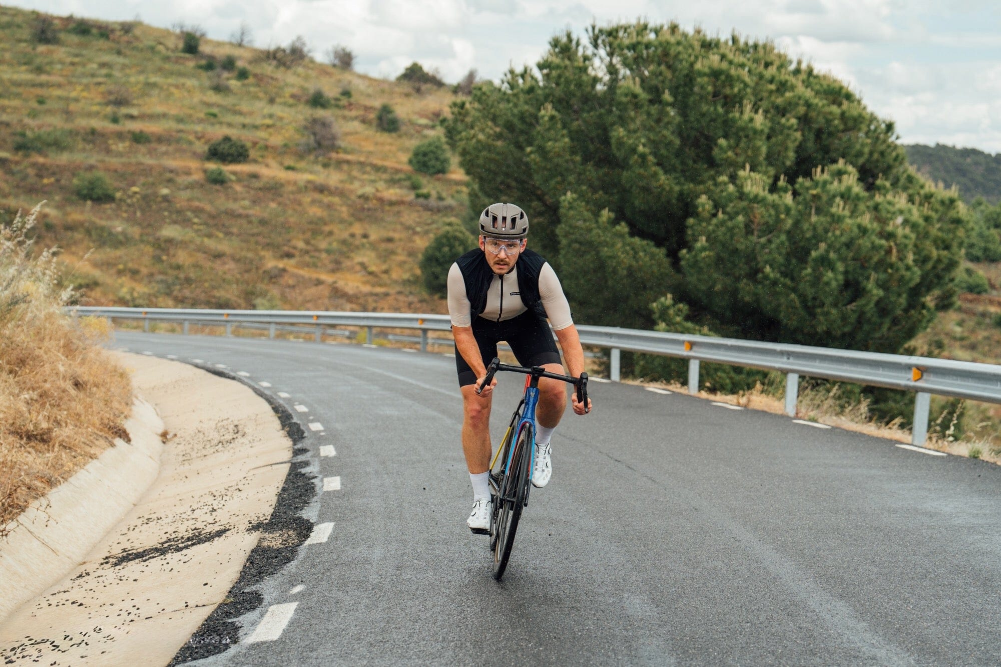 Cyclist riding on a winding road with greenery in the background