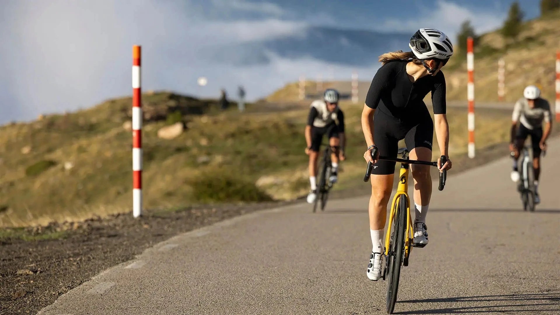 Cyclists riding SCOTT Addict RC bikes on a mountain road, showcasing performance and speed in a high-altitude setting.