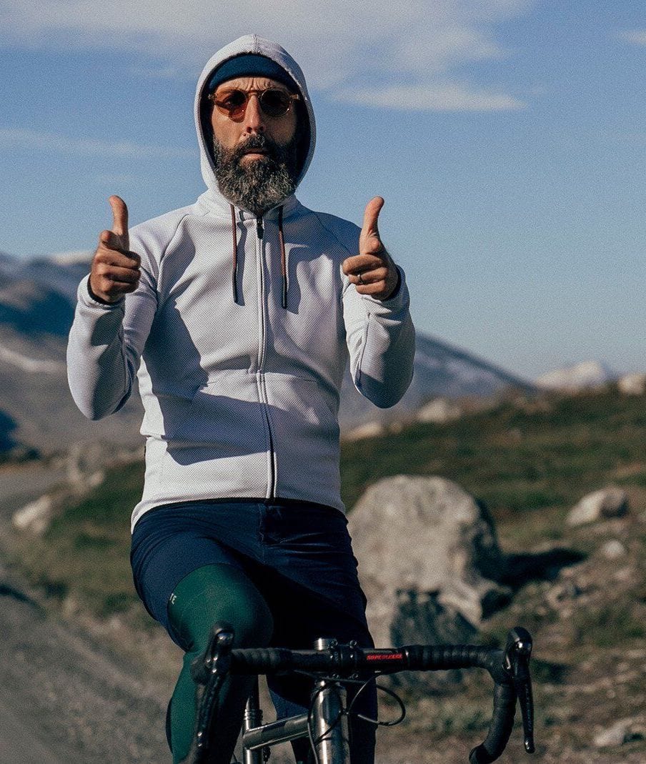 Man giving two thumbs up in a scenic mountainous landscape, symbolizing Bici's commitment to exhilarating cycling experiences and community connection @ Bici.